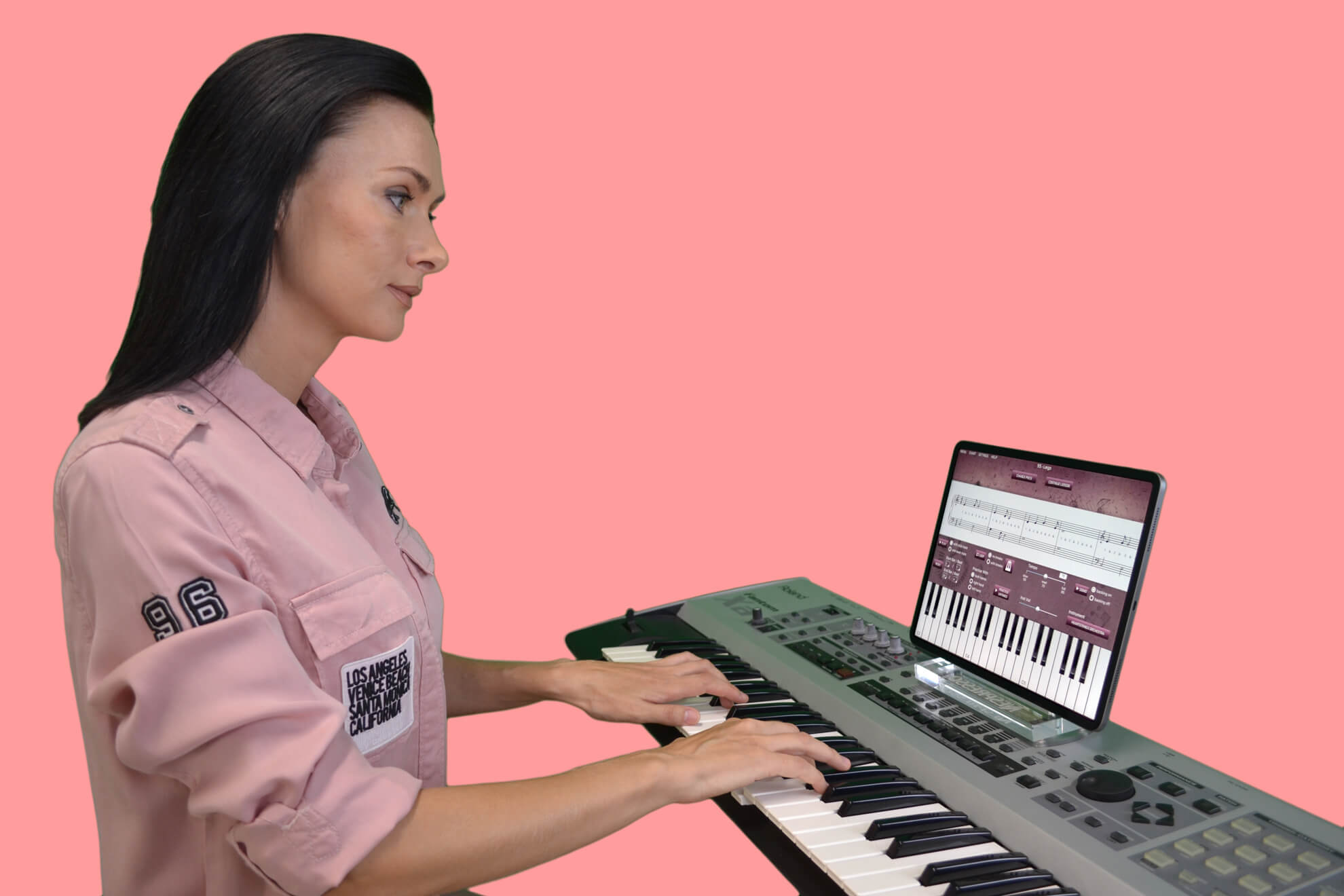 woman in pink shirt playing piano keyboard with online piano lessons app on iPad