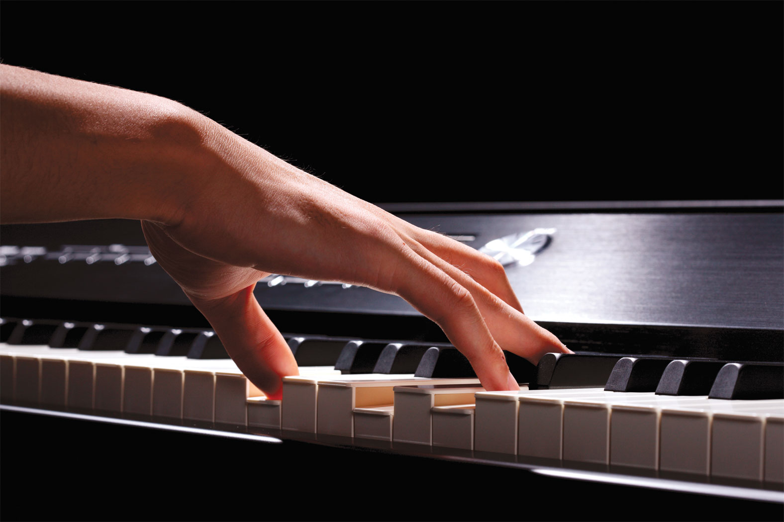 right hand playing a chord on a MIDI keyboard during online piano lesson